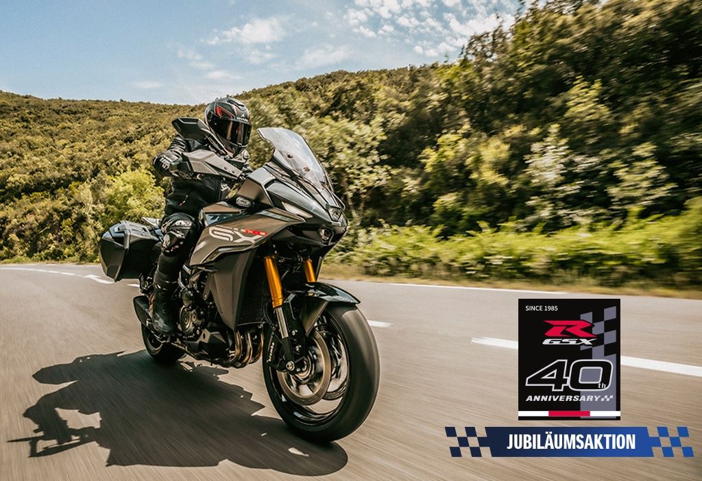 Eine graue GSX-S1000GX auf einer Landstraße, rechts unten mit Jubiläumsaktions-Logo