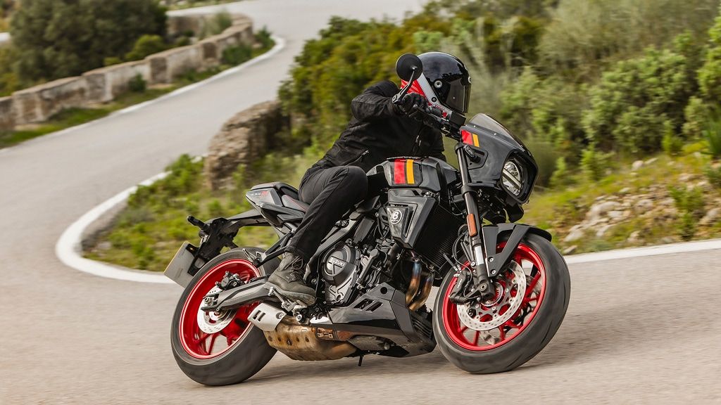 Motorradfahrer in schwarzer Schutzkleidung legt sich mit einer Suzuki GSX-8TT mit roten Felgen dynamisch in eine Kurve auf einer Bergstraße