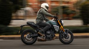 Motorradfahrer mit weißem Helm und grüner Jacke fährt eine Suzuki GSX-8T durch die Stadt, aufgenommen in Seitenansicht mit Bewegungsunschärfe