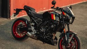 Schwarze Suzuki GSX-8TT mit roten Felgen steht geparkt vor einer roten Wand
