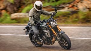 Motorradfahrer mit beiger Jacke und weißem Helm fährt eine Suzuki GSX-8T auf einer Landstraße