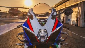 Frontansicht einer Suzuki GSX-R1000R in weiß-blau-rot auf der Rennstrecke bei Sonnenuntergang
