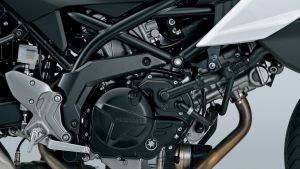 Nahaufnahme des Motors und Rahmens eines Suzuki-Motorrads, mit sichtbaren Leitungen, Metallstrukturen und dem „Suzuki“-Schriftzug auf dem Motorgehäuse.