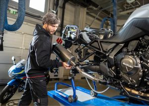 Ein Mechaniker bringt einen neuen Auspuff an einem Motorrad an.