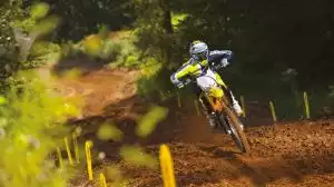 Motocross-Fahrer auf gelbem Suzuki RM-Z Bike in voller Fahrt über einen staubigen Offroad-Parcours.