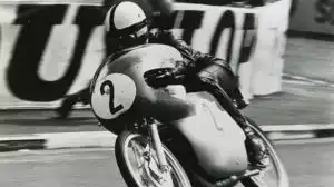 Historischer Motorradrennfahrer auf Suzuki-Maschine in Aktion auf Rennstrecke