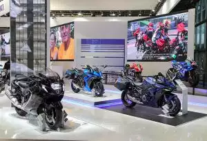 Suzuki Motorräder auf der EICMA-Messe mit digitalen Präsentationen im Hintergrund