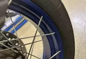 Detailansicht eines Suzuki-Motorradreifens mit Speichenfelge in einer Werkstattumgebung