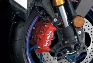 Rote Brembo Bremsen am Vorderrad eines Suzuki Motorrads mit blauer Felge und sportlichen Felgenrandaufklebern.