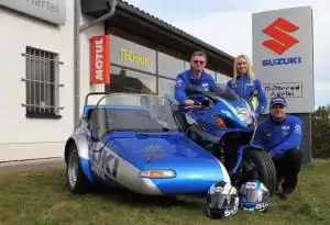 Suzuki Hayabusa MotoGP Gespann vor Suzuki Händler, Team in blauer Kleidung präsentiert Motorrad.