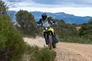 Motorradfahrer auf Suzuki Adventure-Bike auf Schotterweg in bergiger Landschaft