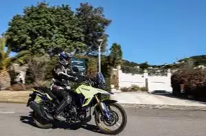 Motorradfahrer auf Suzuki-Motorrad bei sonniger Fahrt auf Landstraße