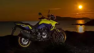 Gelb-blaue Suzuki V-Strom 800DE im Sonnenuntergang am Meer, bereit für das nächste Abenteuer.