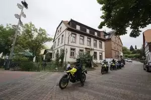 Motorradfahrer auf Suzuki-Motorrädern vor einem historischen Gebäude in einer deutschen Stadt
