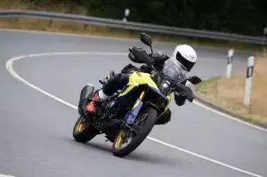 Motorradfahrer auf Suzuki Adventure-Bike in Kurve auf Landstraße.