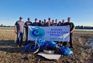 Team von Suzuki-Mitarbeitern beim Clean Ocean Project mit gesammeltem Müll am Strand