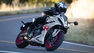 Dynamischer Fahrer auf weißer Suzuki GSX-8R in sportlicher Kurvenlage auf asphaltierter Straße.