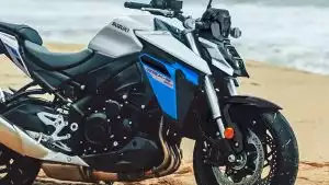 Detailansicht der silbern-blauen Suzuki GSX-S950, geparkt auf Sandstrand vor Meereskulisse.