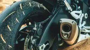 Hinterrad mit Offroad-Schmutz, Bremsscheibe und Auspuff-Endtopf am Adventure-Motorrad.