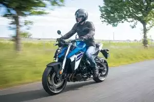 Fahrer auf Suzuki-Motorrad auf Landstraße, umgeben von grüner Landschaft