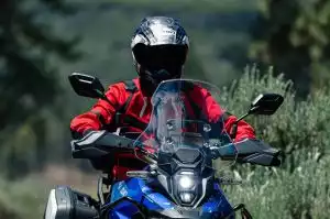 Motorradfahrer in roter Jacke auf Suzuki-Motorrad in natürlicher Umgebung