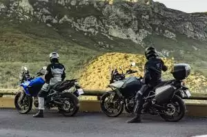 Zwei Motorradfahrer auf Suzuki-Motorrädern genießen die Aussicht auf eine bergige Landschaft.