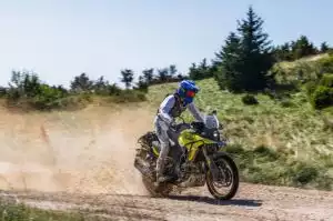 Gelbe Suzuki V-Strom 800DE mit Fahrer auf staubigem Offroad-Trail, während der Bosnia Rally 2023.