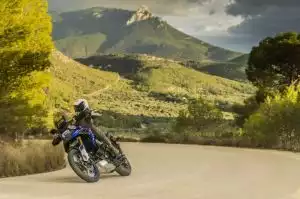 Blaues Suzuki Motorrad auf kurviger Straße in malerischer Berglandschaft