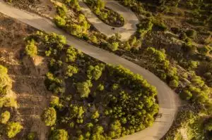 Motorradfahrer auf kurviger Straße in bewaldeter Landschaft in Frankreich