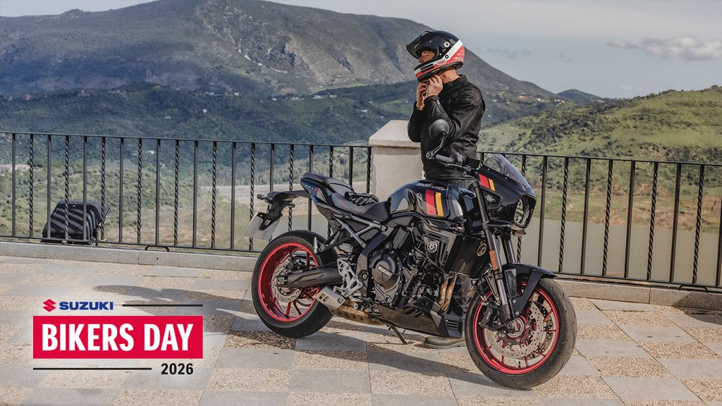 Suzuki GSX-8TT im Café-Racer-Design mit roten Felgen vor Bergpanorama, daneben ein Fahrer in Lederjacke. Im Bild der Hinweis auf den Suzuki Bikers Day 2026.