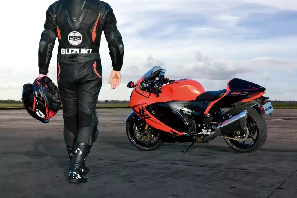 Motorradfahrer in Suzuki-Lederkombi neben roter Suzuki Hayabusa auf Asphalt