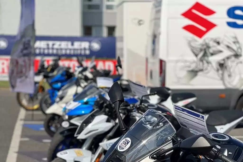 Motorräder bei einer Suzuki-Veranstaltung mit Werbebannern im Hintergrund.