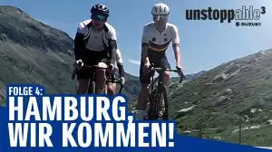 Zwei Radfahrer in den Bergen mit Suzuki-Logo und Text 'Hamburg, wir kommen!'
