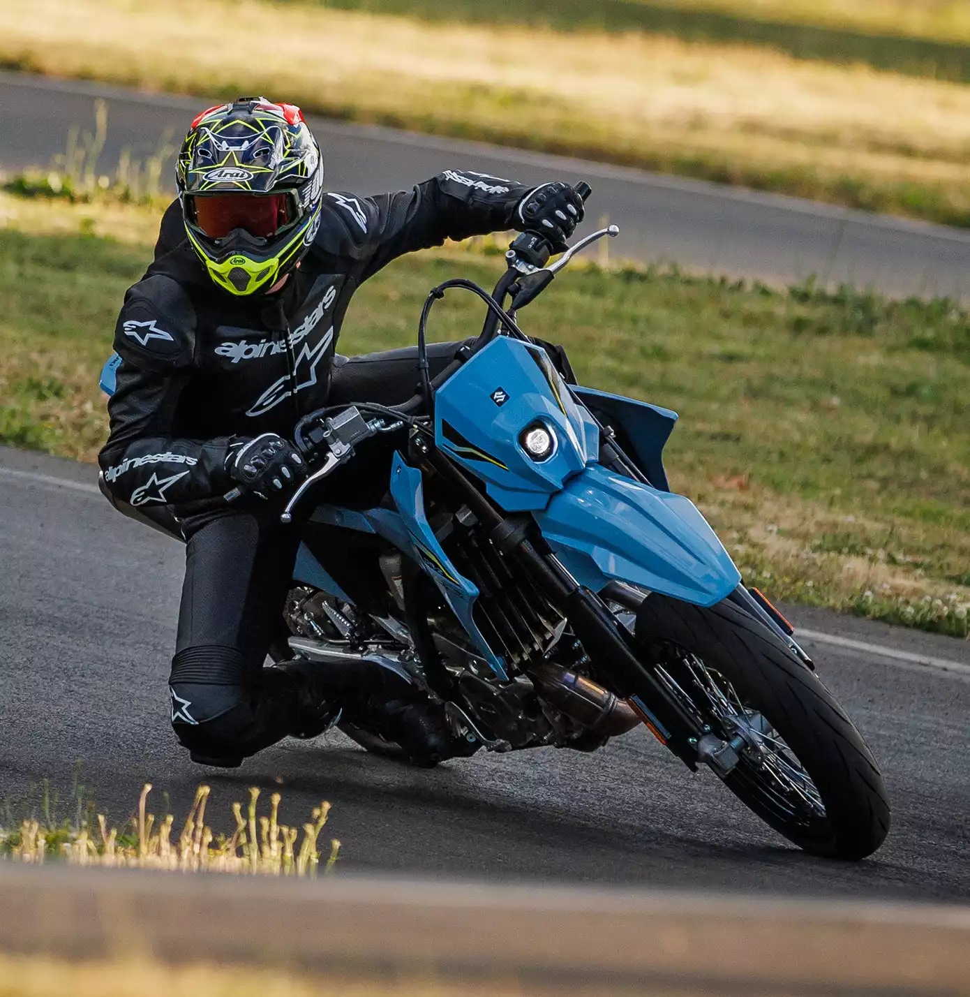 Fahrer auf Suzuki DR-Z4SM Motorrad in Kurvenlage auf Rennstrecke