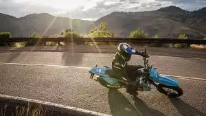 Fahrer auf blauem Suzuki DR-Z4S Motorrad in Kurve bei Sonnenuntergang