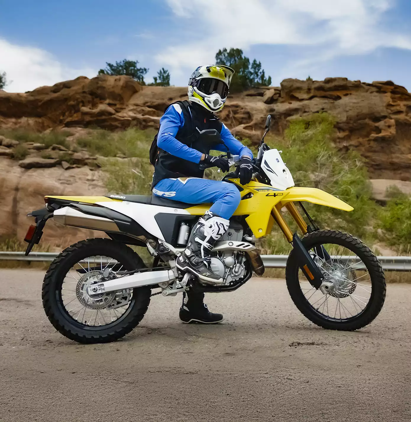 Gelbes Suzuki DR-Z4S Motorrad in Offroad-Umgebung mit Fahrer in blauer Schutzkleidung