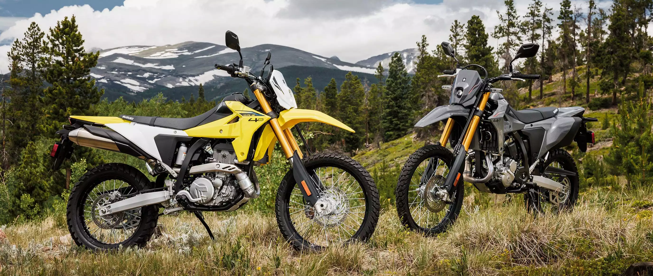 Zwei Suzuki DR-Z4S Motorräder in gelb und grau in bergiger Landschaft