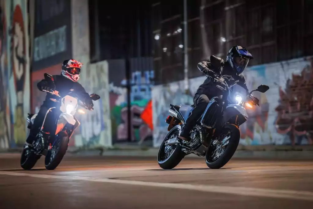 Zwei Suzuki Fahrer in der Dämmerung in einer urbanen Umgebung mit Graffiti an den Wänden.