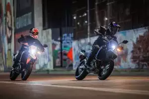Zwei Suzuki Fahrer in der Dämmerung in einer urbanen Umgebung mit Graffiti an den Wänden.