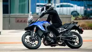 Fahrer auf Suzuki V-Strom 800 in der Stadt, Seitenansicht des Adventure-Bikes in Fahrt.