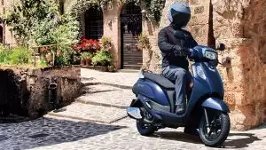 Der neue Suzuki Address 125 in stilvollem Matt Blau vor mediterraner Kulisse – kompakt, wendig und bereit für urbane Abenteuer mit Komfort und Charakter.