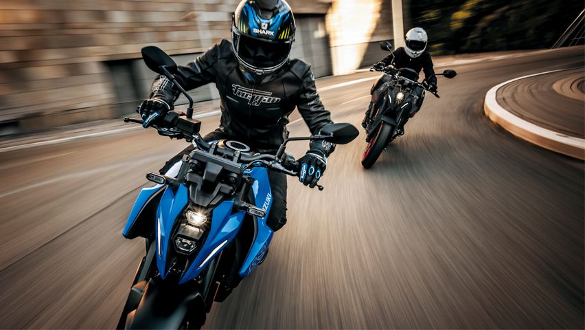 Zwei Suzuki GSX-8S in sportlicher Kurvenfahrt, vorne in Blau mit LED-Scheinwerfer, dahinter ein schwarzes Modell in Schräglage.
