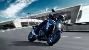 Fahrer in dunkler Kleidung dynamisch in der Kurve auf blauer GSX-S1000, LEDs leuchten.