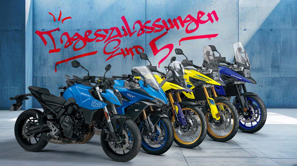 5 verschiedene Suzuki Motorradmodelle auf grauem Betonboden, leicht versetzt nebeneinander angeordnet. Eine GSX-8S und eine GSX-S1000GT in  hellblauer Farbe, eine V-Strom 800DE und eine V-Strom 1050DE in gelber Farbe und eine V-Strom 1050 in dunkelblauer Farbe. Im Hintergrund eine hellblaue Wand mit Schriftzug im Graffiti-Look: "Tageszulassungen/Euro 5".