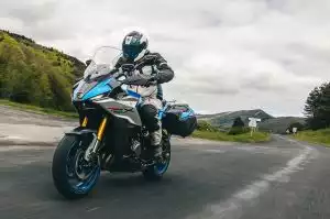Suzuki GSX-S1000GX Power Edition: Fahrer auf blau-silbernem Tourenmotorrad mit Seitenkoffern in dynamischer Fahrt.