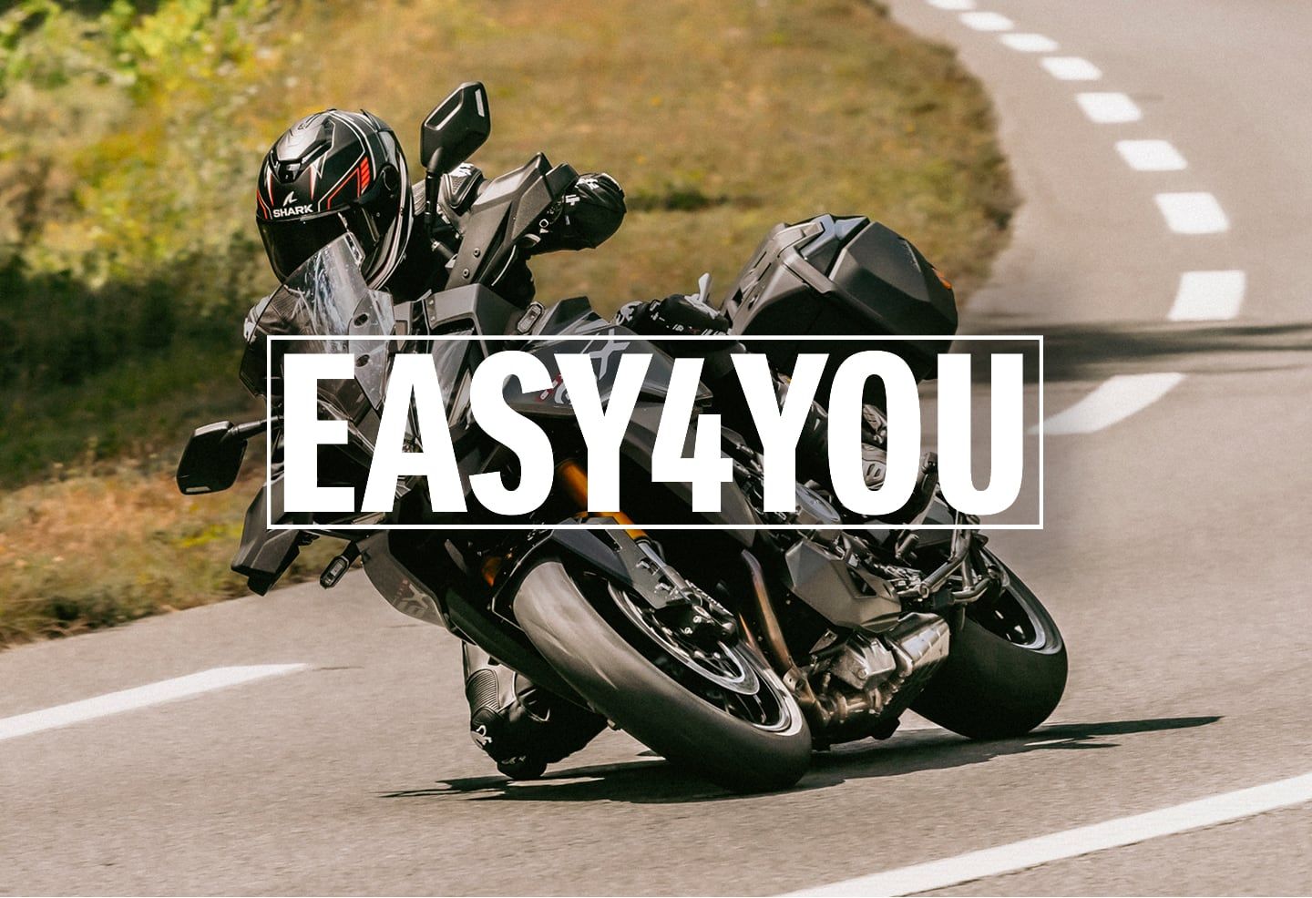 Ein Motorradfahrer auf einer schwarzen GSX-S1000GX fährt dynamisch über eine Landstraße. Im Vordergrund steht der Hinweis auf die „EASY4YOU" Finanzierung