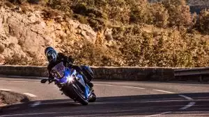 Suzuki GSX-S1000GT Travel Edition: Fahrer auf blauem Tourenmotorrad in dynamischer Kurvenfahrt auf Gebirgsstraße.