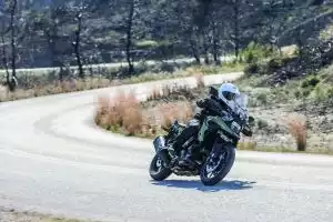 Fahrer auf grüner Suzuki V-Strom 1050 in dynamischer Schräglage auf einer kurvigen Bergstraße.