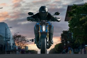 Frontansicht mit Fahrer mit einer Suzuki GSX-S1000 auf der Straße. Leuchtende LED-Scheinwerfer betonen das Design im Stadtbild.