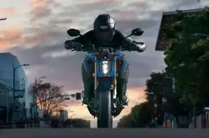 Frontansicht mit Fahrer mit einer Suzuki GSX-S1000 auf der Straße. Leuchtende LED-Scheinwerfer betonen das Design im Stadtbild.